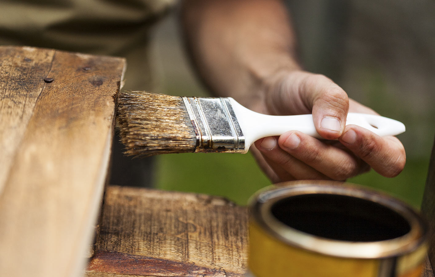 Holz wird mit Holzschutzmittel bearbeitet eingepinselt